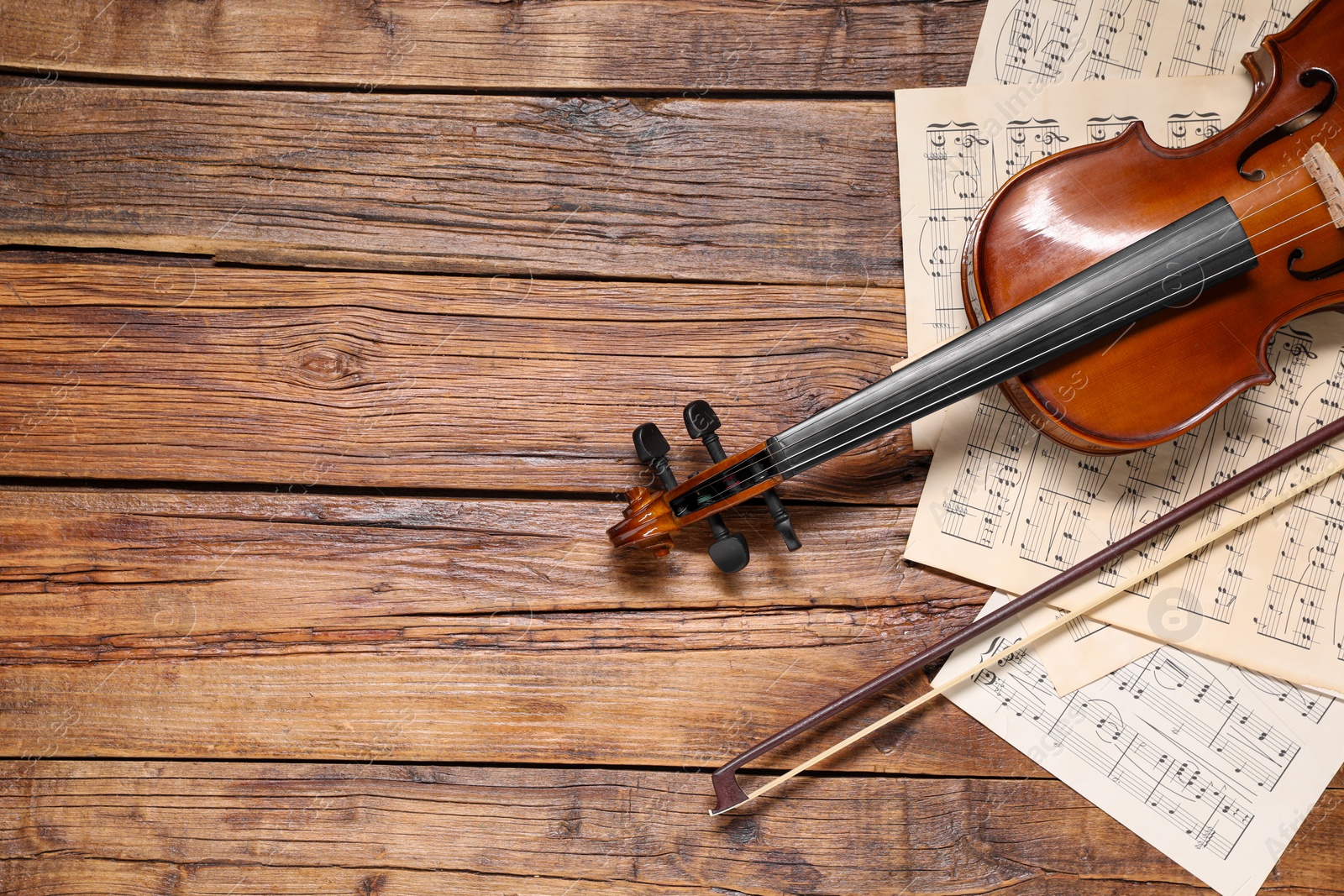 Photo of Violin, bow and music sheets on wooden table, top view. Space for text