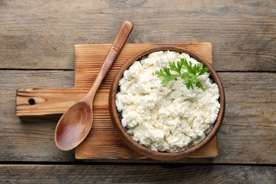 Photo of Delicious fresh cottage cheese with parsley on wooden table, top view
