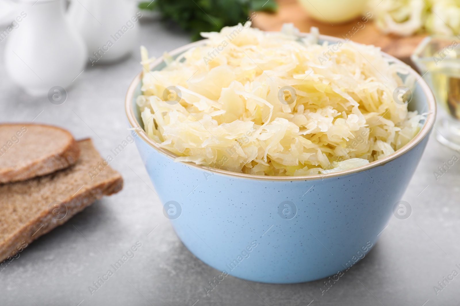 Photo of Bowl of tasty sauerkraut on grey table, closeup