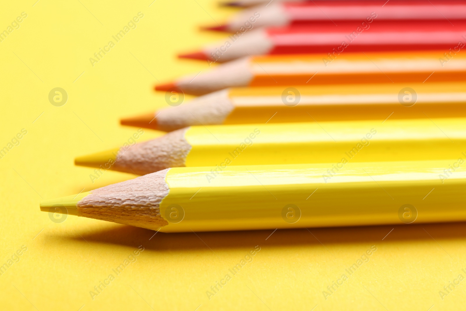 Photo of Different color pencils on yellow background, closeup