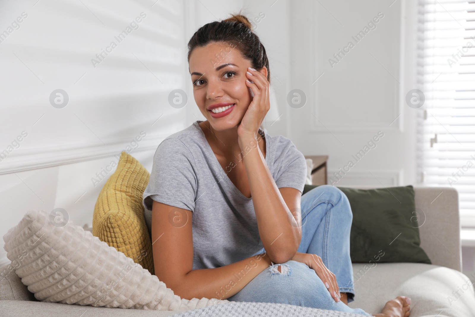Photo of Beautiful woman sitting on sofa at home