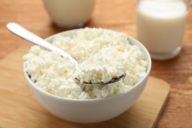 Photo of Delicious fresh cottage cheese in bowl on wooden table, closeup