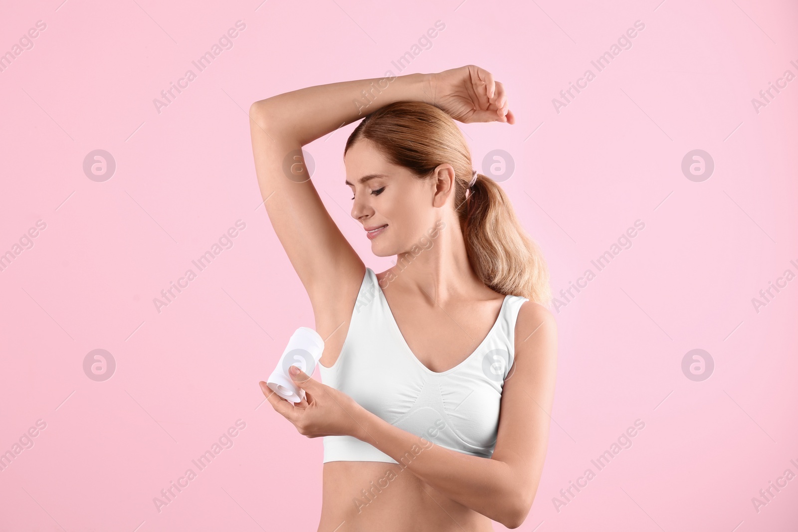 Photo of Young woman using deodorant on color background