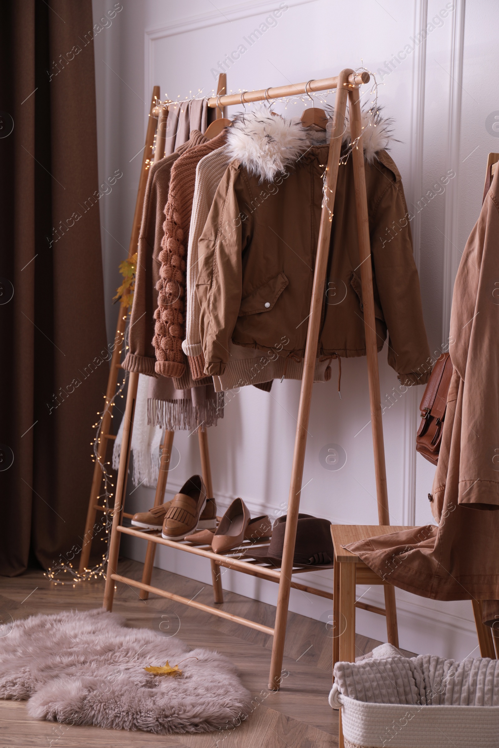 Photo of Rack with stylish warm clothes, shoes and accessories in modern dressing room