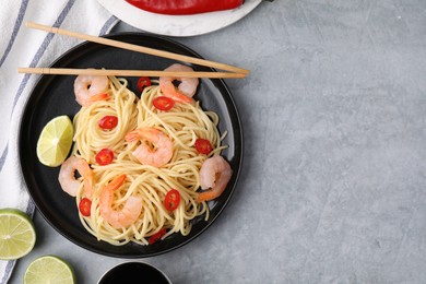 Photo of Tasty spaghetti with shrimps, chili pepper and lime on grey table, flat lay. Space for text