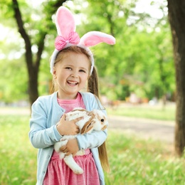 Little girl with adorable bunny outdoors on sunny day. Easter celebration