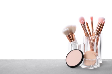 Organizer with makeup brushes and powder on grey table