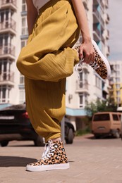 Photo of Woman wearing sneakers with leopard print outdoors, closeup