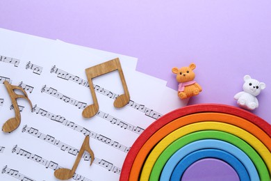 Photo of Wooden notes, music sheets and toys on violet background, top view. Baby song concept