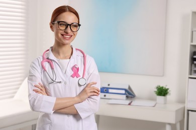 Photo of Mammologist with pink ribbon in hospital, space for text. Breast cancer awareness