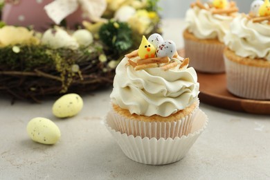 Tasty Easter cupcakes with vanilla cream and festive decor on gray table