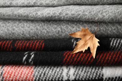 Photo of Dry leaf on stack of soft folded plaids, closeup