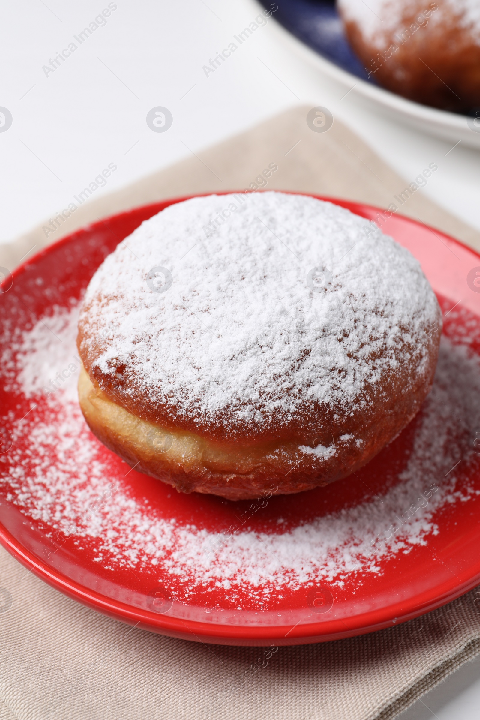 Photo of Delicious sweet bun with powdered sugar on table, closeup