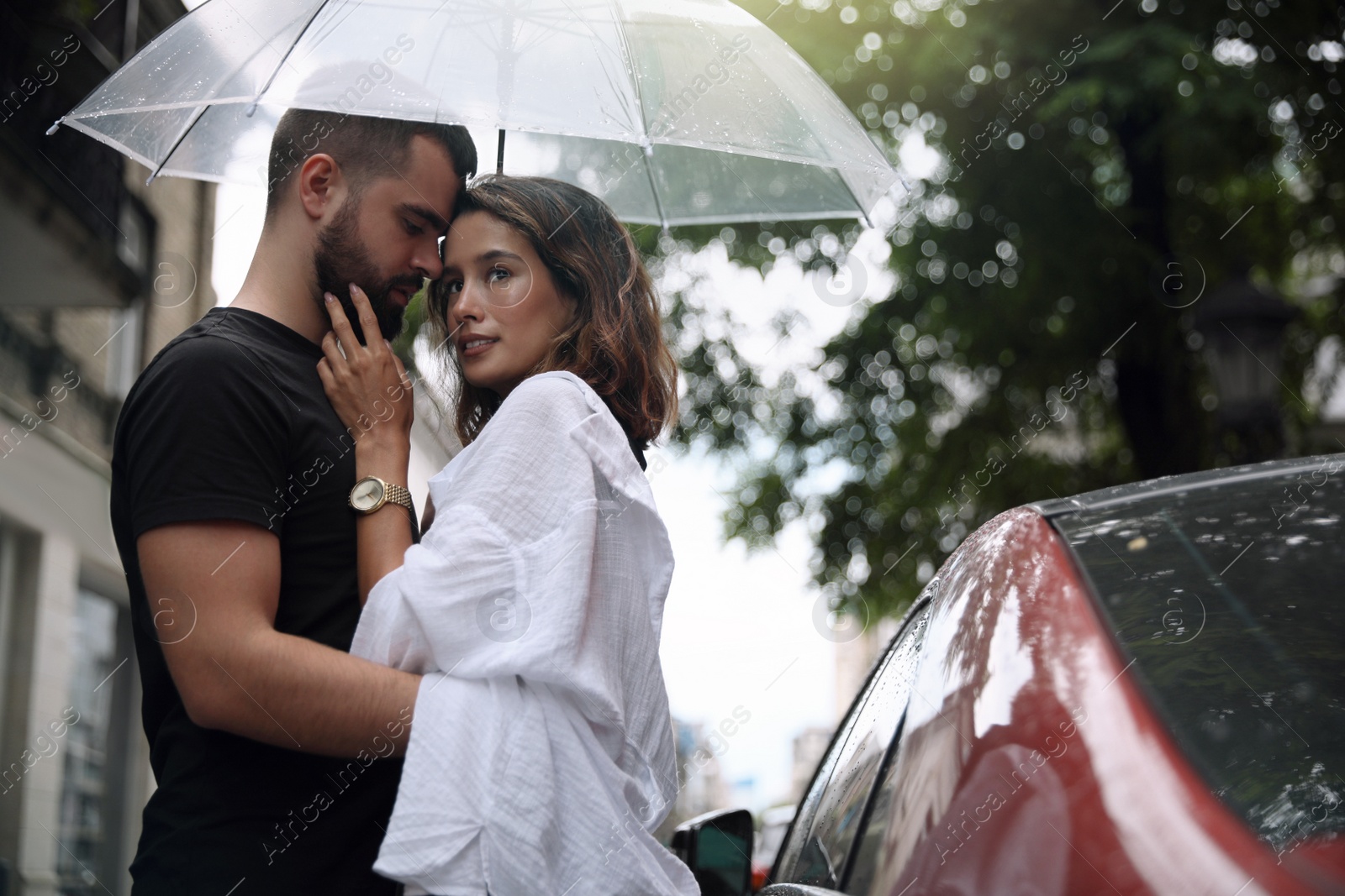 Photo of Young couple with umbrella enjoying time together under rain on city street, space for text