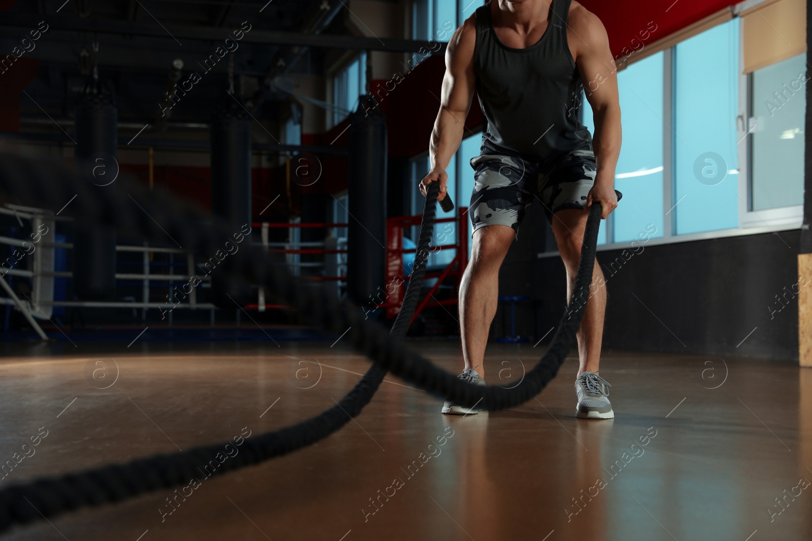 Photo of Man working out with battle ropes in modern gym, closeup