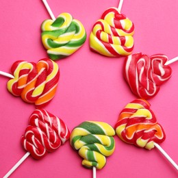 Photo of Sweet lollipops on pink background, flat lay
