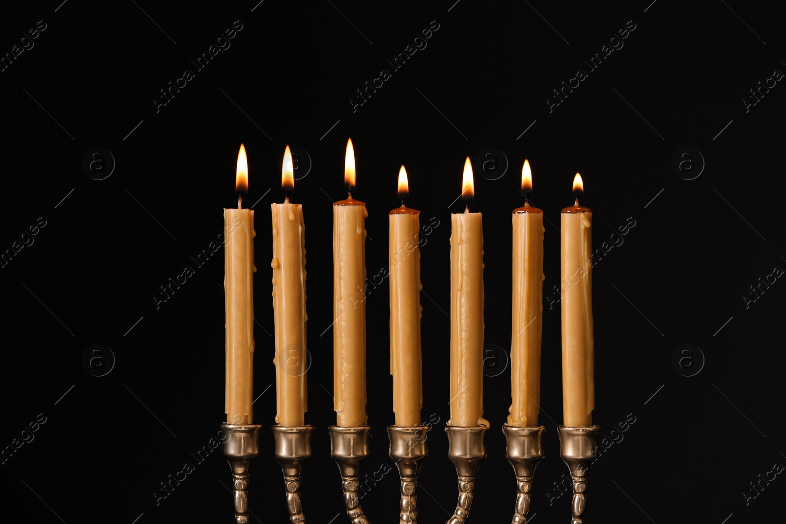 Photo of Golden menorah with burning candles on black background