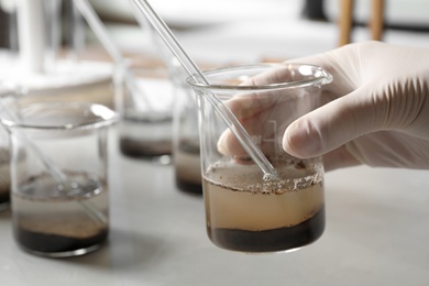 Scientist preparing soil extract at table, closeup. Laboratory analysis