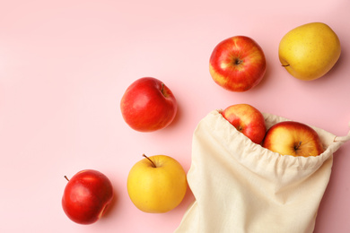 Photo of Cotton eco bag and apples on pink background, flat lay