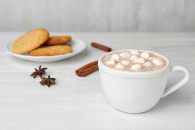 Photo of Delicious hot cocoa drink with marshmallows in cup on white wooden table