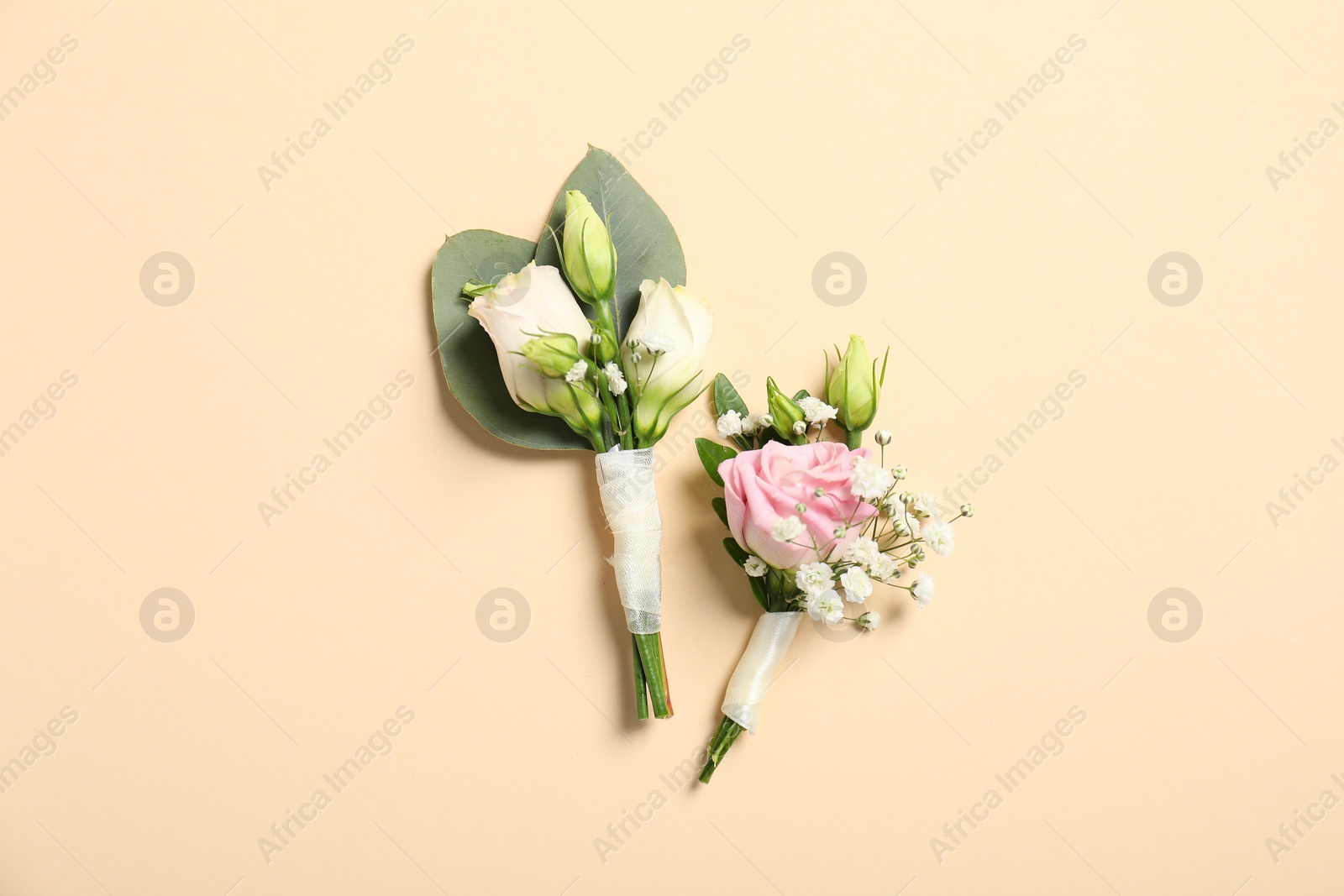 Photo of Wedding stuff. Stylish boutonnieres on beige background, top view