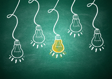 Image of Idea concept. Light bulbs drawn on green chalkboard