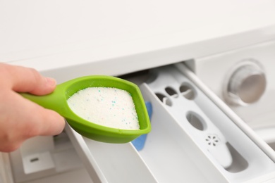 Photo of Woman pouring powder into drawer of washing machine, closeup. Laundry day