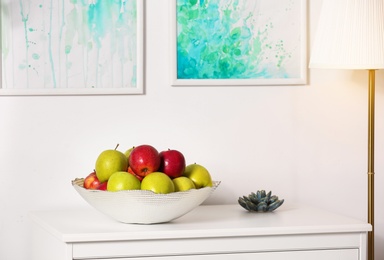 Photo of Bowl with different sweet apples on commode in room