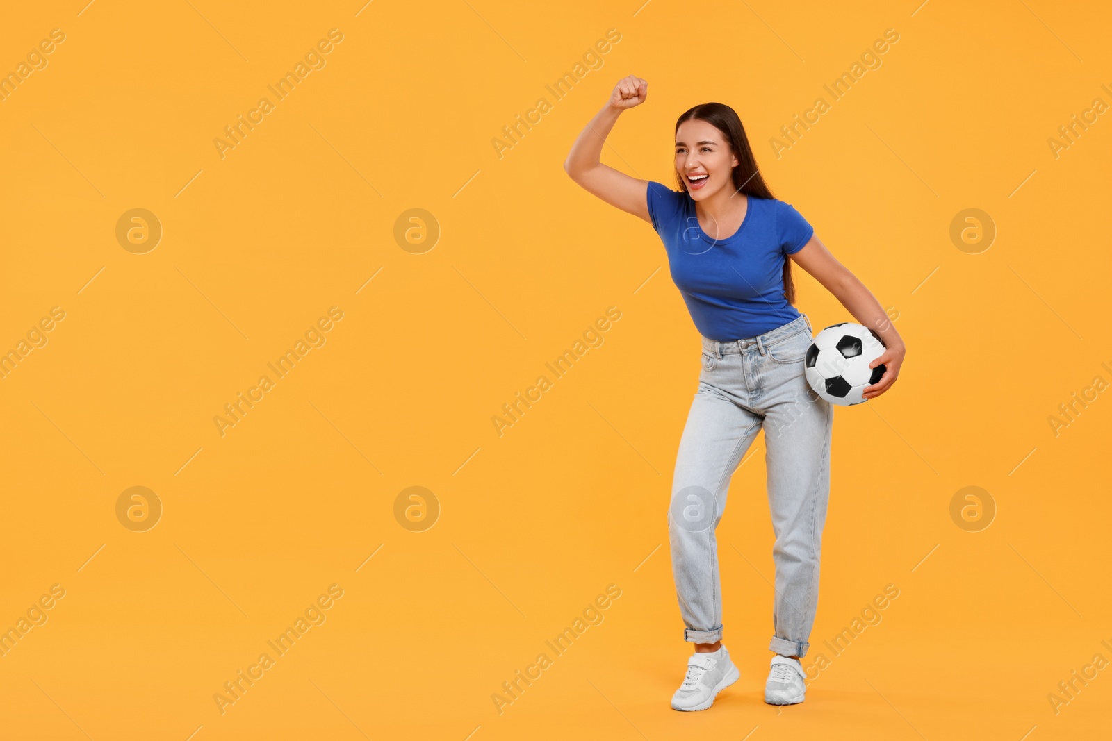 Photo of Happy fan with soccer ball celebrating on yellow background, space for text