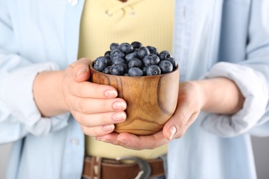 Photo of Woman holding tasty fresh blueberries, closeup view