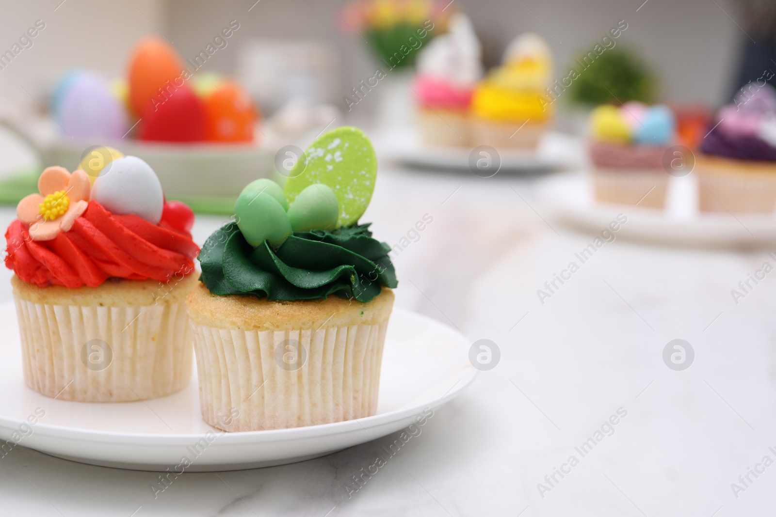 Photo of Tasty decorated Easter cupcakes on white marble table, closeup. Space for text