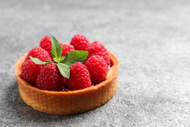 Tartlet with fresh raspberries on light grey background, closeup and space for text. Delicious dessert
