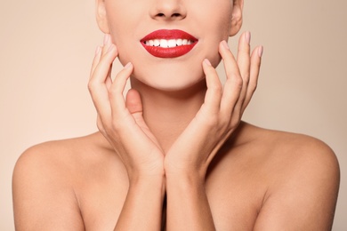 Beautiful young woman with red lips on color background, closeup