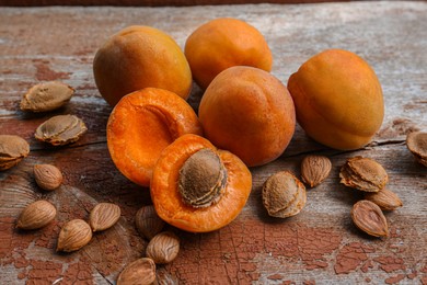 Photo of Delicious ripe apricots with stones on wooden table, closeup