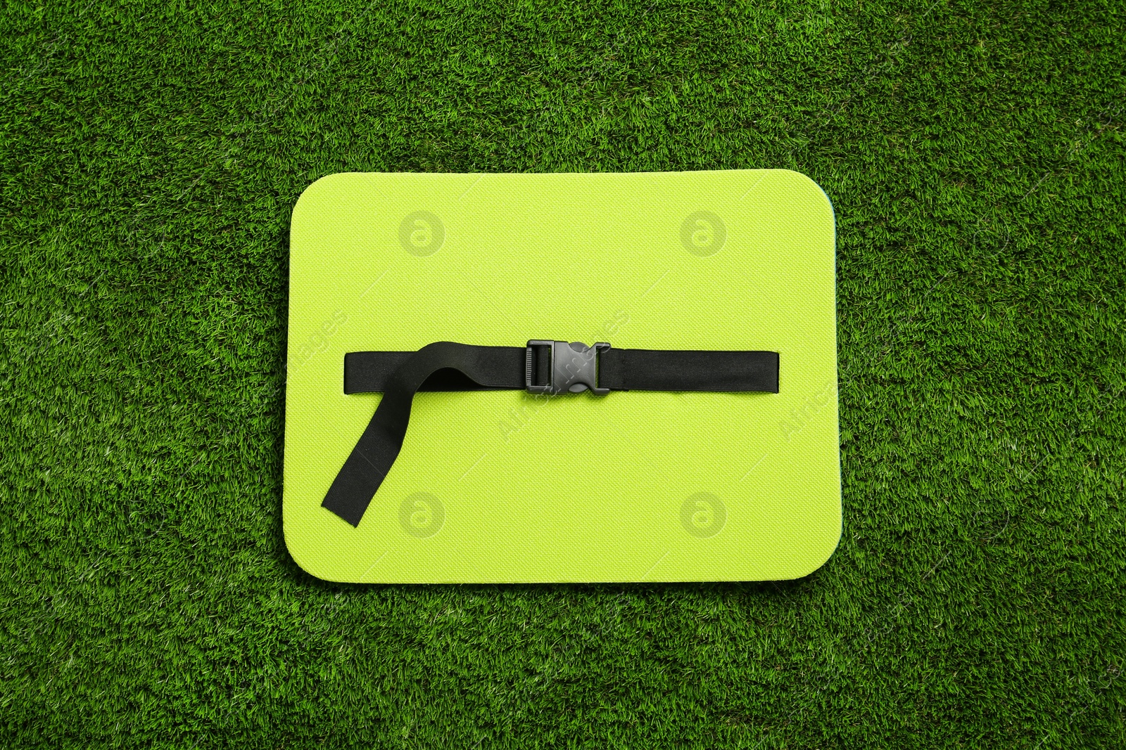 Photo of Bright foam seat mat for tourist on green grass, top view