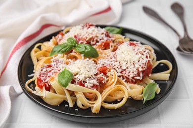 Photo of Delicious pasta with tomato sauce, basil and parmesan cheese on white tiled table, closeup