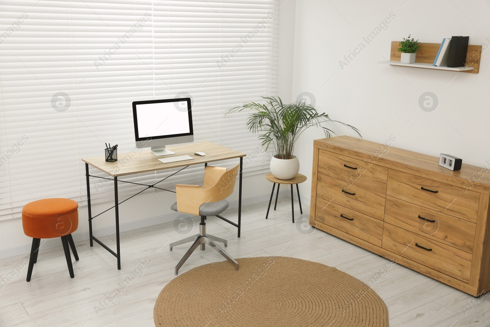 Photo of Stylish office interior with comfortable chair, desk, computer and houseplant