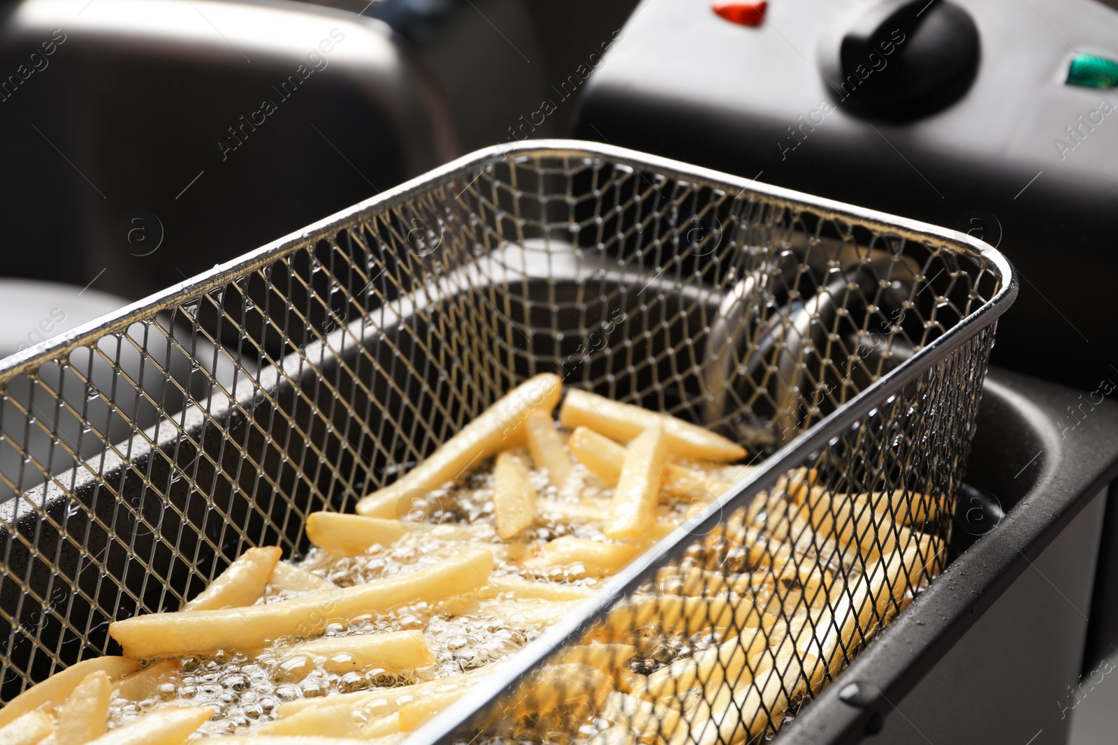 Photo of Cooking delicious french fries in hot oil, closeup