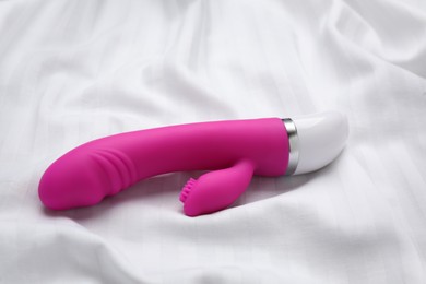 Photo of Pink vibrator on white fabric. Sex toy