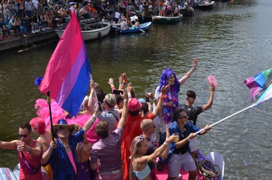 AMSTERDAM, NETHERLANDS - AUGUST 06, 2022: Many people in boats at LGBT pride parade on river