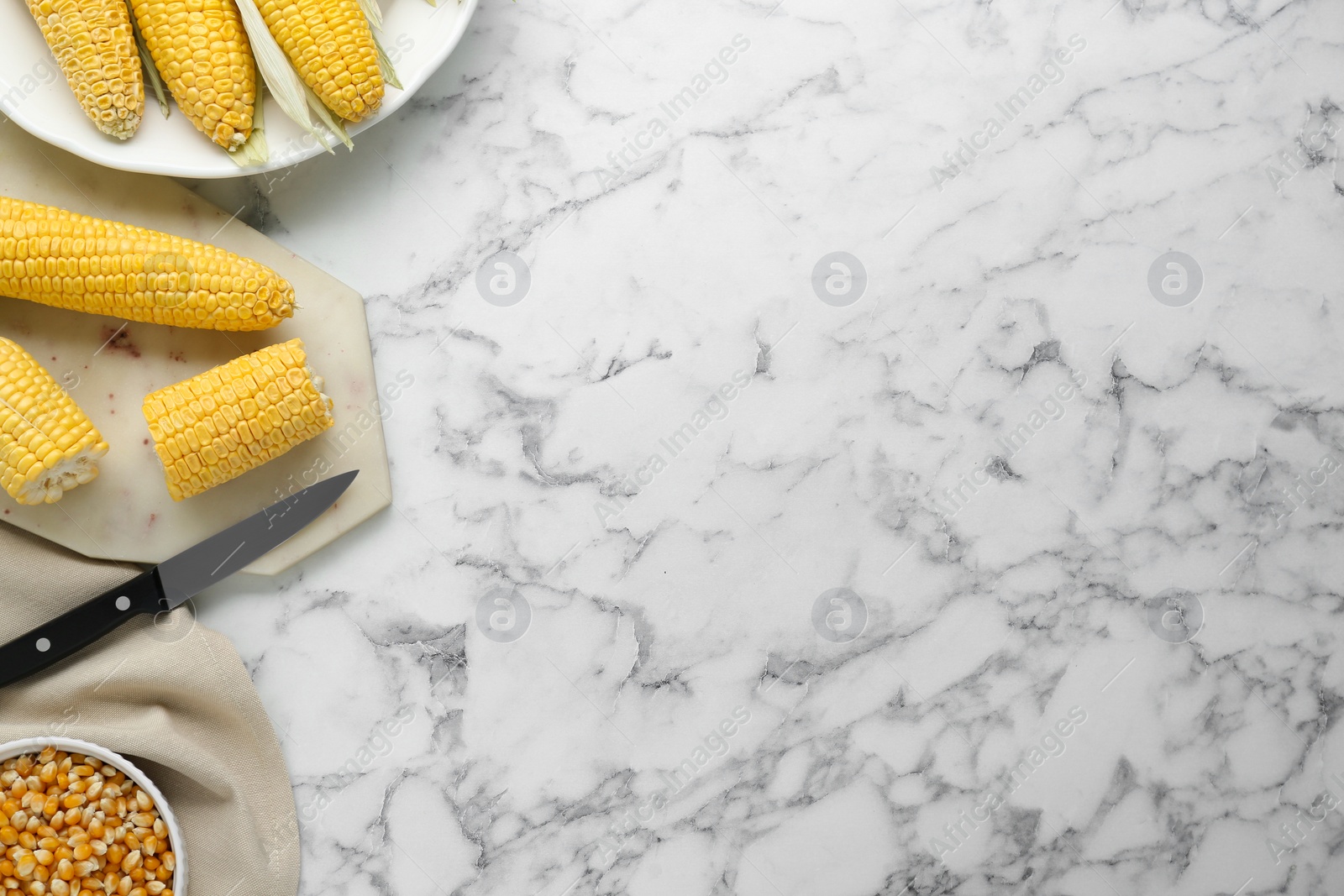 Photo of Tasty fresh corn cobs and kernels on white marble table, flat lay. Space for text