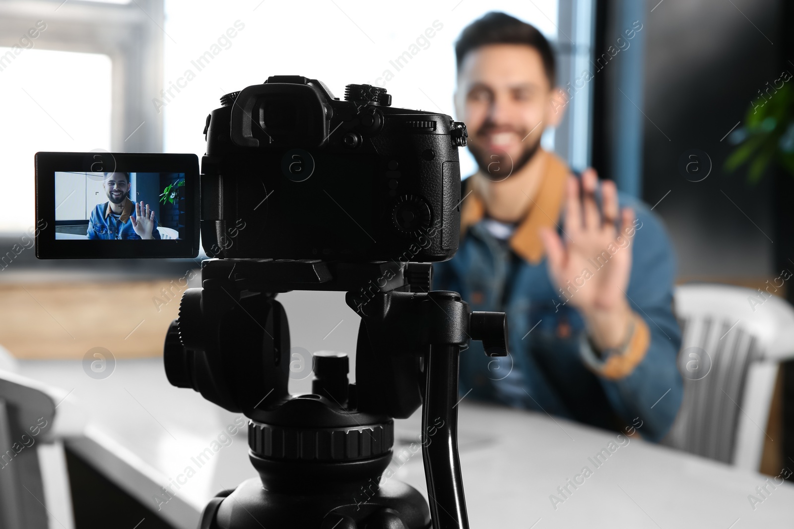 Photo of Young blogger recording video at cafe, focus on camera screen