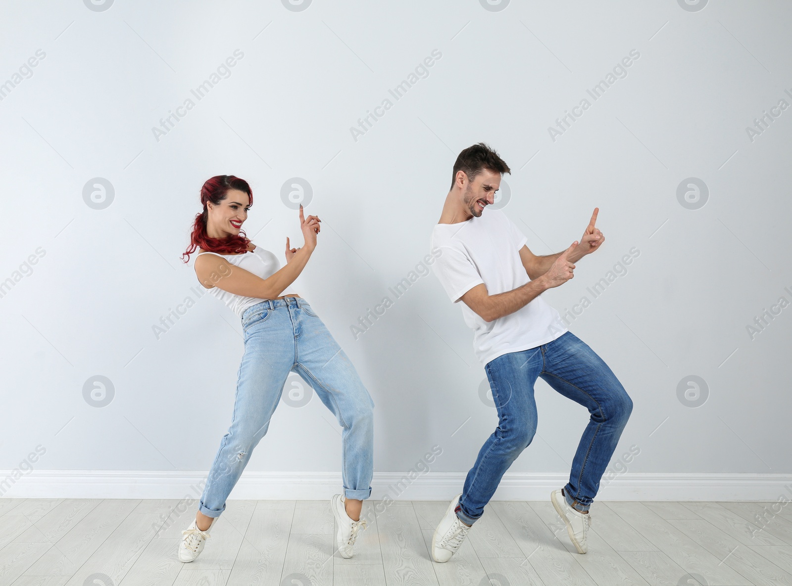 Photo of Beautiful young couple dancing near light wall