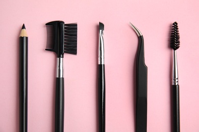 Photo of Set of professional eyebrow tools on pink background, flat lay