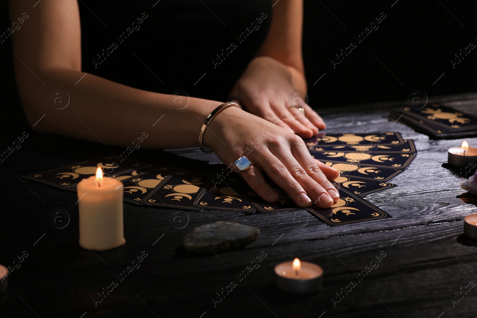 Photo of Soothsayer predicting future with tarot cards at table in darkness, closeup