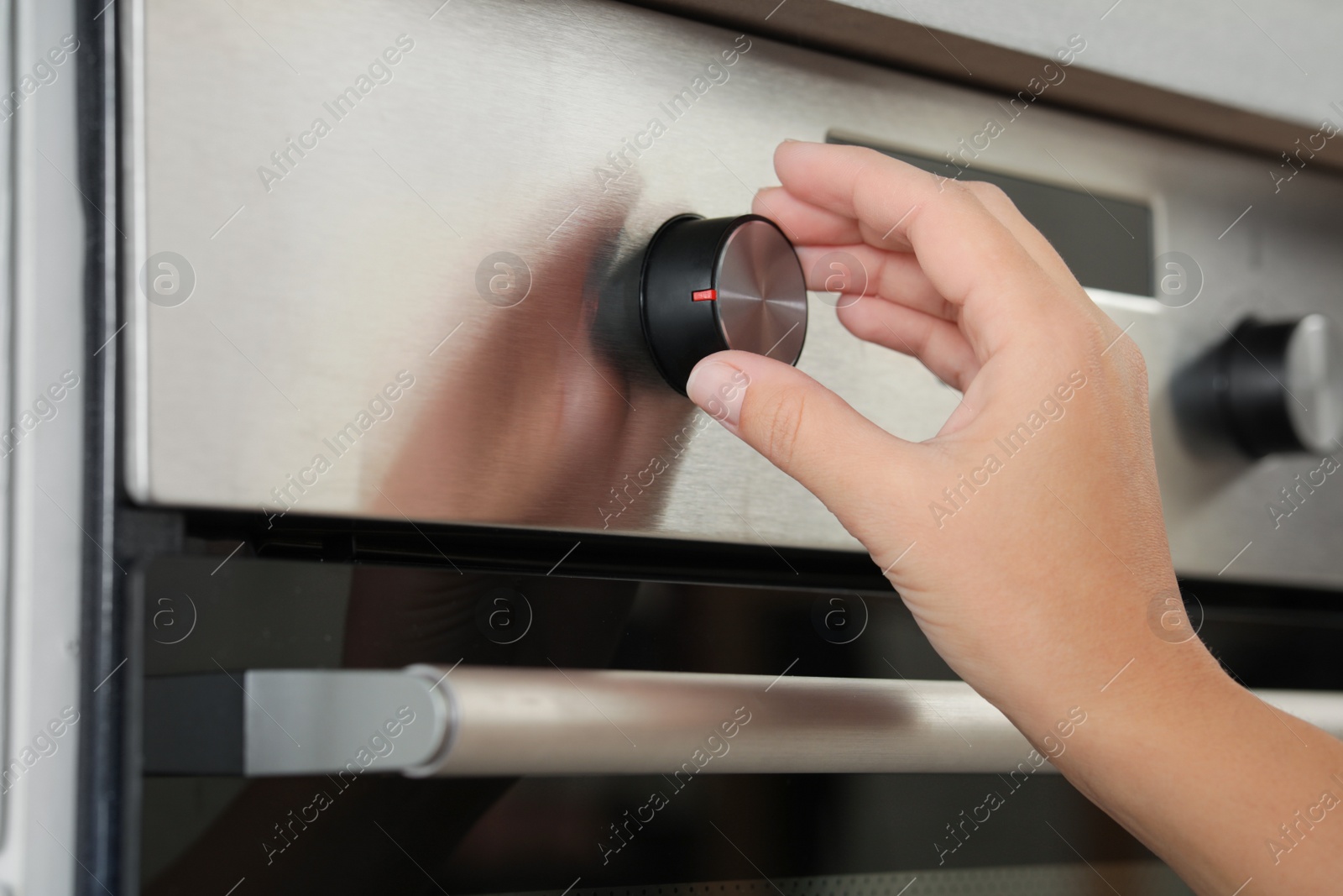 Photo of Woman regulating cooking mode on oven panel, closeup