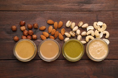Different types of delicious nut butters and ingredients on wooden table, flat lay