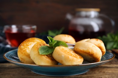 Photo of Delicious cottage cheese pancakes with jam and mint on wooden table