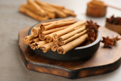Photo of Aromatic cinnamon sticks and anise on grey table, closeup