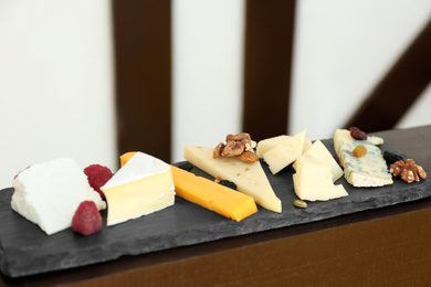 Photo of Different types of delicious cheeses and snacks on slate plate